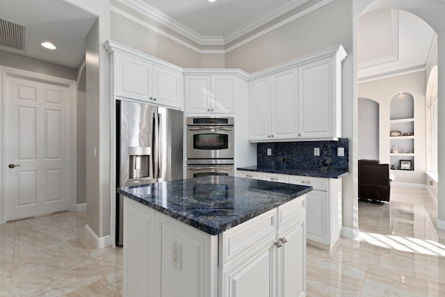 kitchen featuring dark stone countertops, a center island, white cabinets, and stainless steel appliances