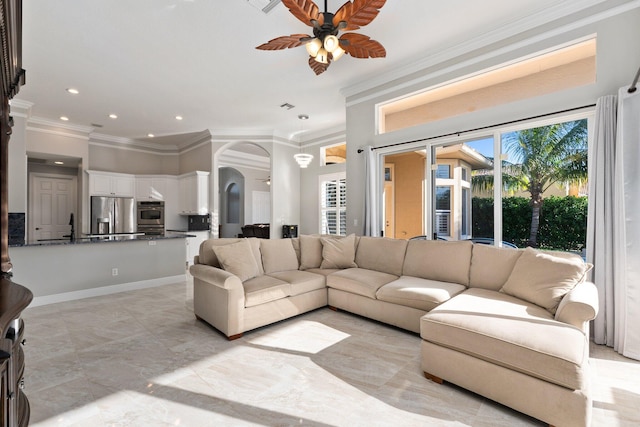 living room with a healthy amount of sunlight, ceiling fan, crown molding, and sink