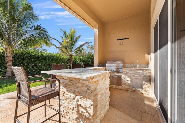 view of patio with area for grilling, a grill, and exterior bar