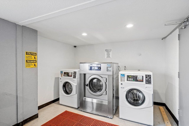 clothes washing area with washer and clothes dryer and a textured ceiling