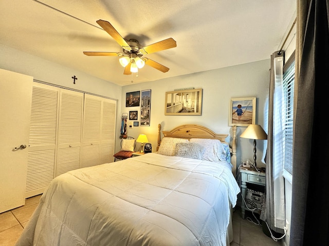 bedroom with ceiling fan, light tile patterned floors, and a closet