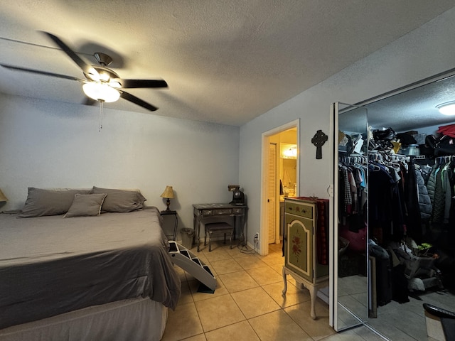 tiled bedroom with ensuite bath, ceiling fan, a closet, and a textured ceiling