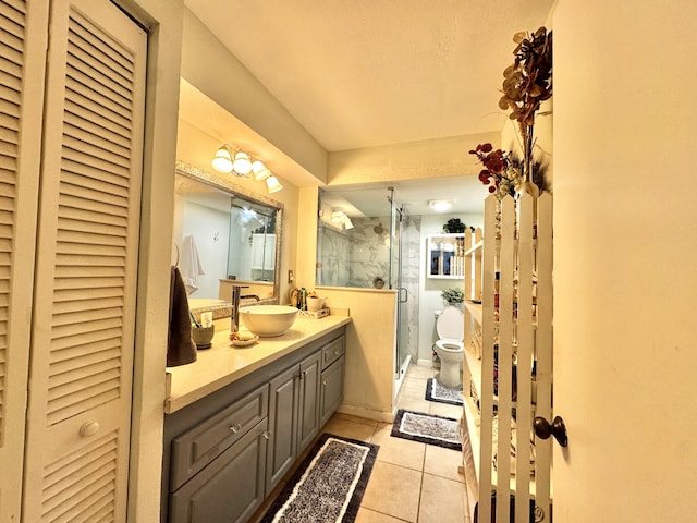 bathroom featuring tile patterned floors, vanity, toilet, and a shower with shower door