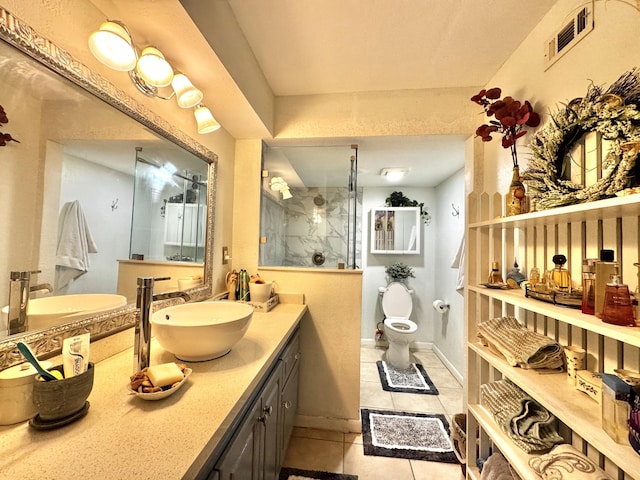 bathroom featuring toilet, vanity, tiled shower, and tile patterned floors