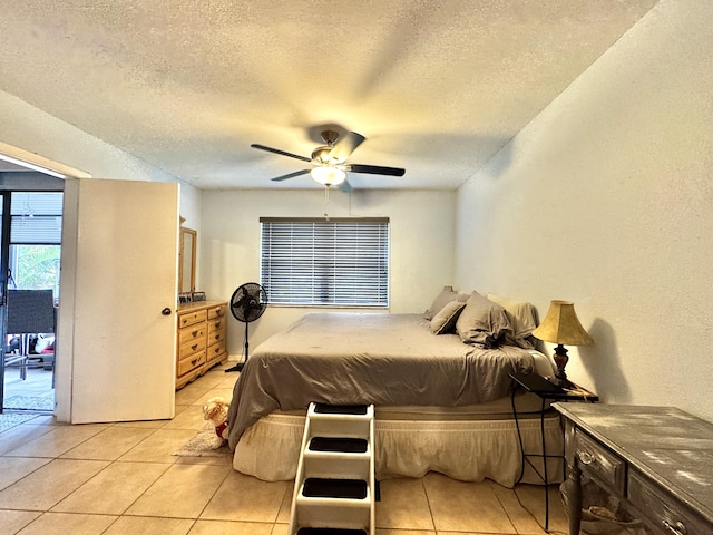 bedroom with ceiling fan, light tile patterned floors, and a textured ceiling