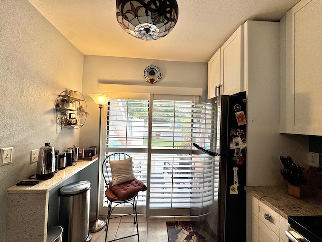 kitchen with light stone countertops, white cabinets, and fridge