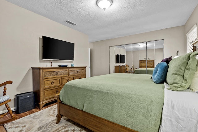 bedroom featuring hardwood / wood-style flooring, a textured ceiling, and a closet