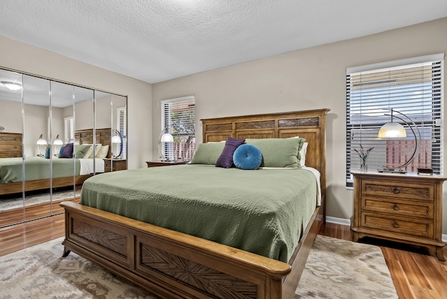 bedroom with a textured ceiling, light hardwood / wood-style flooring, and a closet