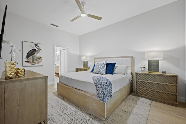 bedroom featuring visible vents, baseboards, ensuite bath, light wood-style flooring, and ceiling fan