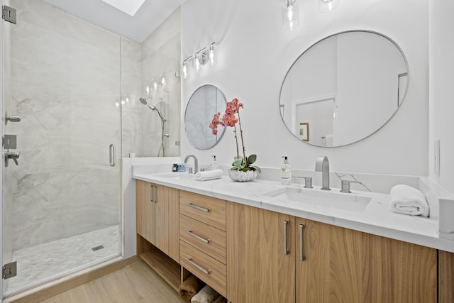 bathroom with a sink, a marble finish shower, and double vanity