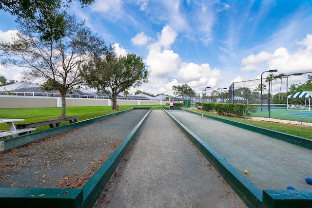 view of community featuring a tennis court and fence