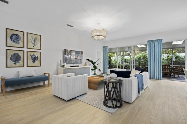 living area featuring a chandelier, light wood-type flooring, and visible vents