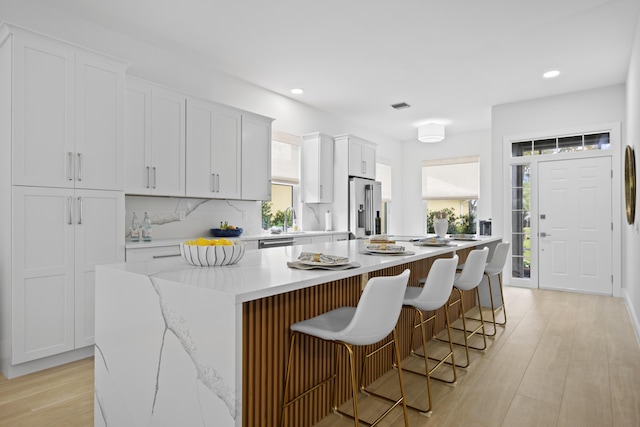 kitchen with light wood-style flooring, white cabinetry, a sink, a kitchen island, and high end refrigerator