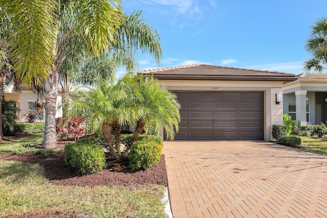 view of front of house featuring stucco siding, a tile roof, decorative driveway, and a garage