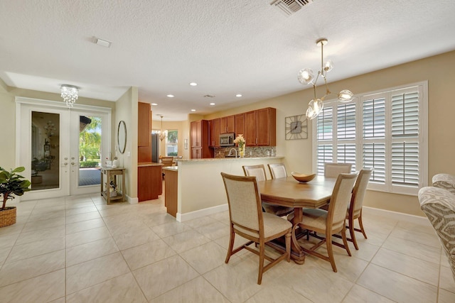 dining space featuring a notable chandelier, light tile patterned floors, and french doors