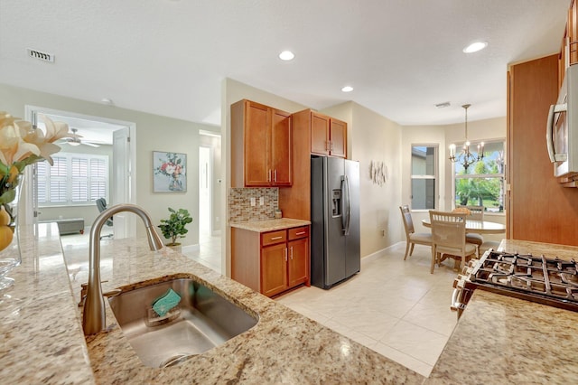 kitchen with backsplash, sink, hanging light fixtures, stainless steel fridge, and light tile patterned floors