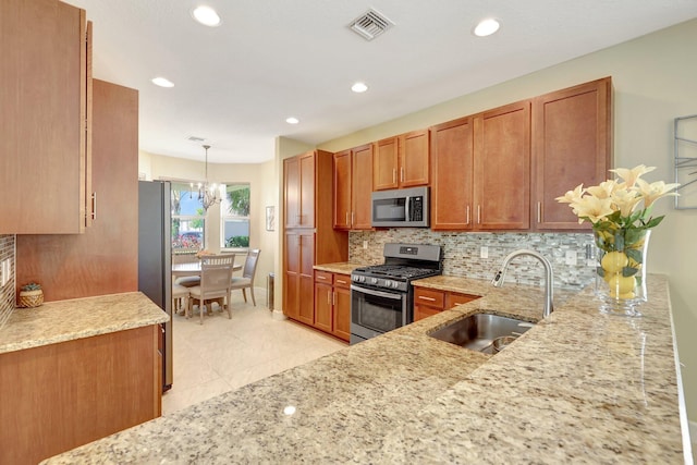 kitchen featuring appliances with stainless steel finishes, tasteful backsplash, sink, pendant lighting, and a chandelier