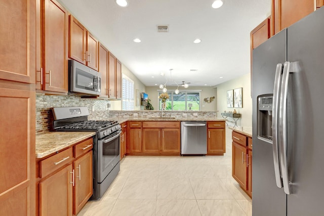 kitchen with ceiling fan, light stone countertops, kitchen peninsula, and appliances with stainless steel finishes