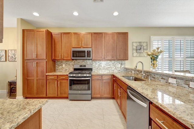 kitchen featuring sink, stainless steel appliances, tasteful backsplash, light stone counters, and light tile patterned floors