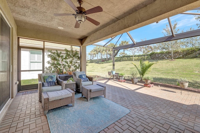 view of patio / terrace featuring glass enclosure, ceiling fan, and an outdoor living space