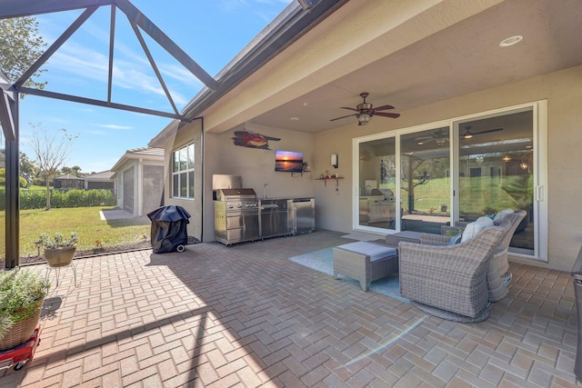 view of patio with glass enclosure, ceiling fan, sink, and area for grilling