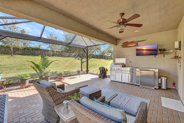 view of patio / terrace featuring glass enclosure, sink, ceiling fan, a grill, and exterior kitchen