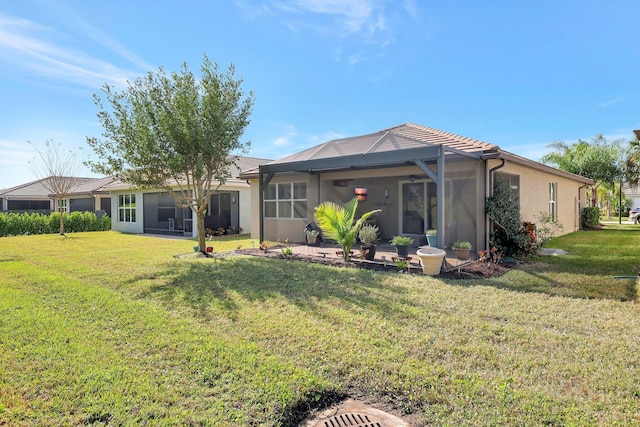 back of property with glass enclosure and a yard