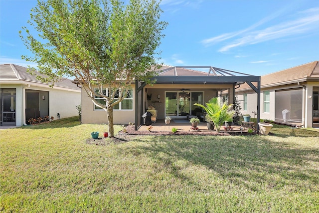 back of property with a lawn, a patio area, and ceiling fan