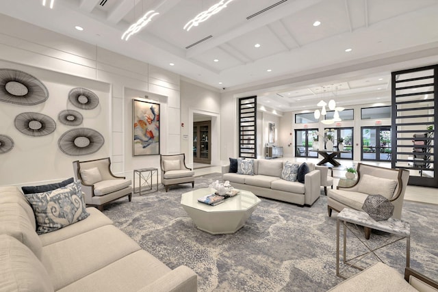 living room featuring an inviting chandelier, a high ceiling, a tray ceiling, and french doors