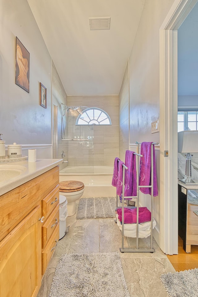 bathroom featuring toilet, vanity, and tiled shower