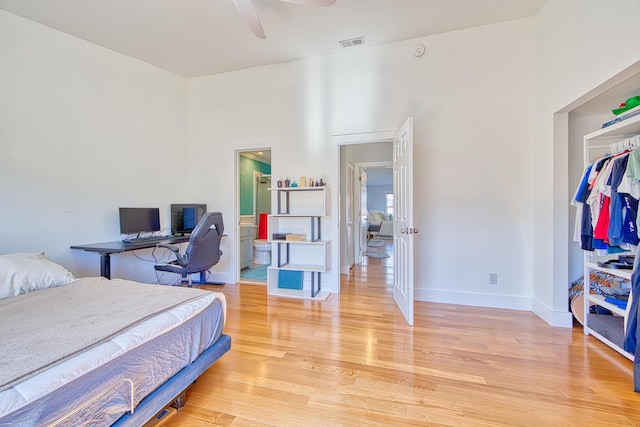 bedroom featuring ceiling fan, light hardwood / wood-style floors, connected bathroom, and a closet