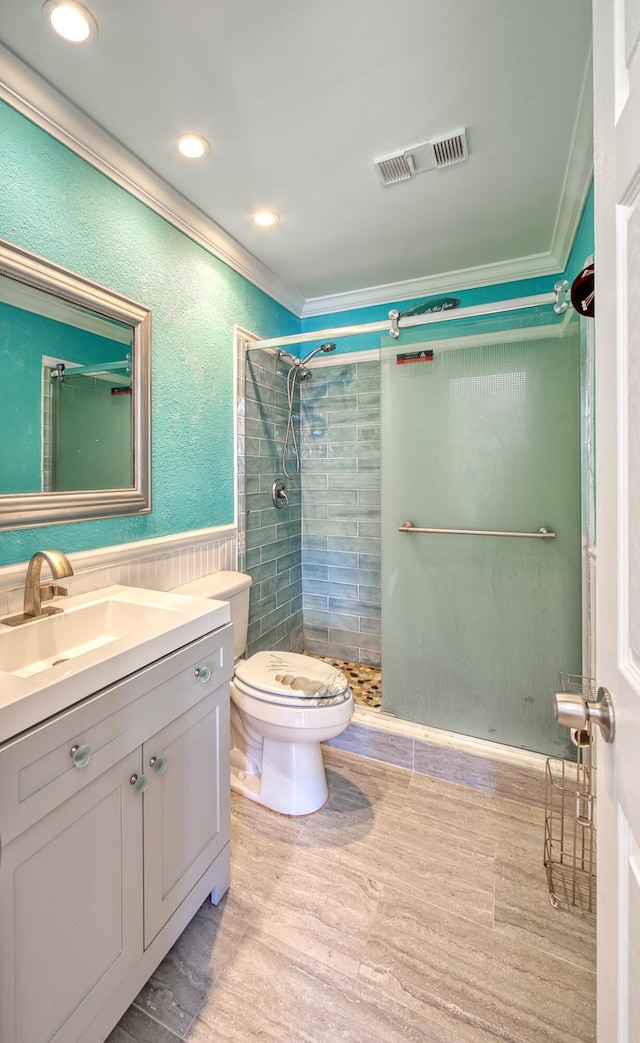 bathroom with ornamental molding, a tile shower, vanity, wood-type flooring, and toilet