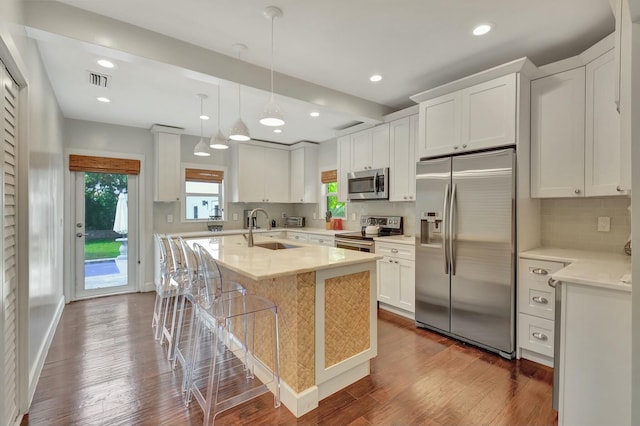 kitchen with appliances with stainless steel finishes, white cabinetry, hanging light fixtures, and sink