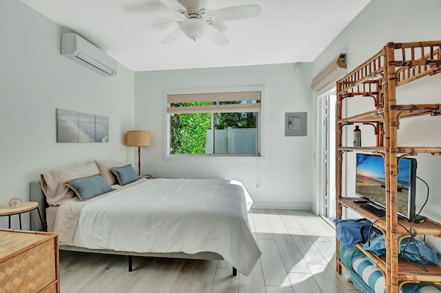 bedroom with a wall unit AC, ceiling fan, and light hardwood / wood-style floors