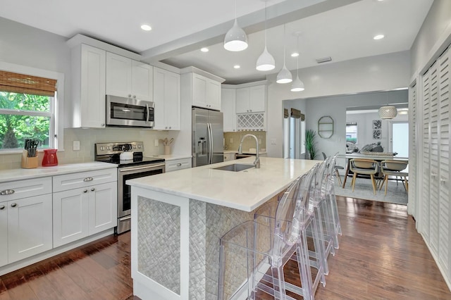 kitchen featuring white cabinets, appliances with stainless steel finishes, a kitchen island with sink, and sink