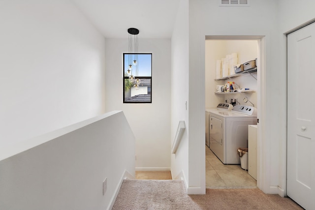 hallway with separate washer and dryer and light carpet