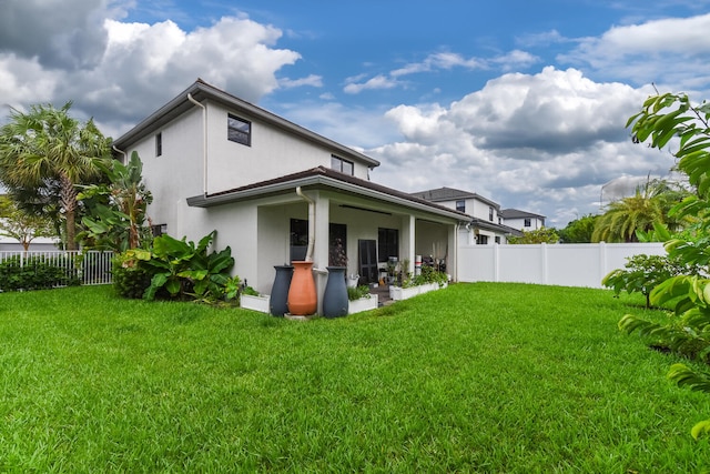 back of property with a yard and ceiling fan