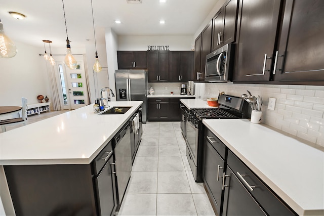 kitchen featuring sink, stainless steel appliances, an island with sink, pendant lighting, and light tile patterned floors