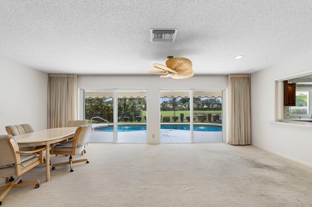 carpeted dining room featuring ceiling fan, a wealth of natural light, and a textured ceiling