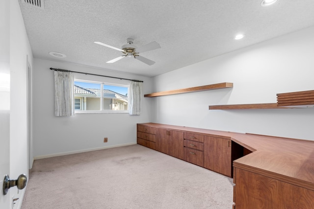 unfurnished office featuring ceiling fan, a textured ceiling, and light carpet