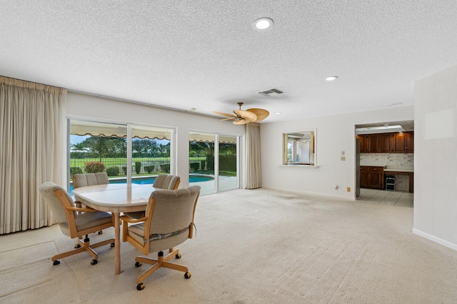 carpeted dining room featuring a textured ceiling and ceiling fan