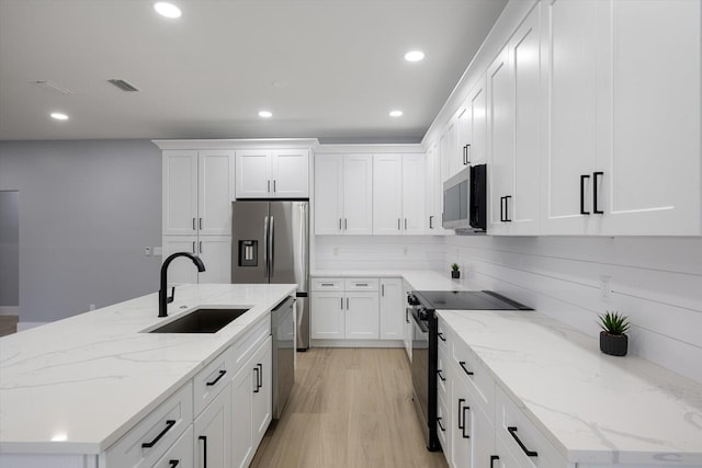 kitchen featuring light stone countertops, sink, white cabinets, and stainless steel appliances