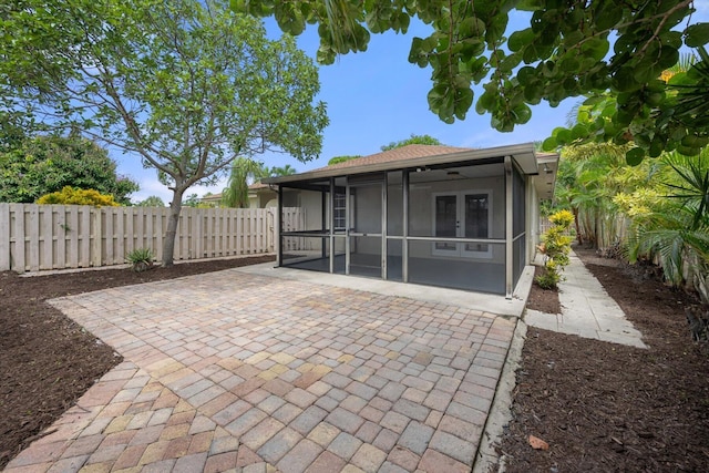 rear view of property with ceiling fan, a patio area, and a sunroom