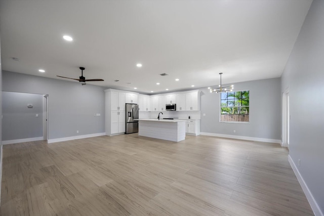 unfurnished living room with ceiling fan with notable chandelier, light hardwood / wood-style floors, and sink