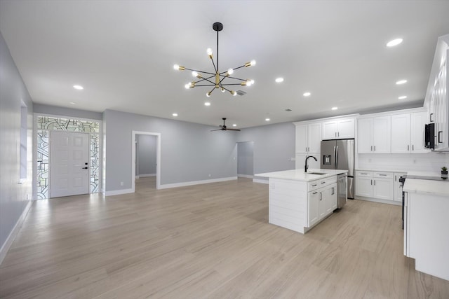 kitchen featuring white cabinetry, a kitchen island with sink, ceiling fan with notable chandelier, and appliances with stainless steel finishes