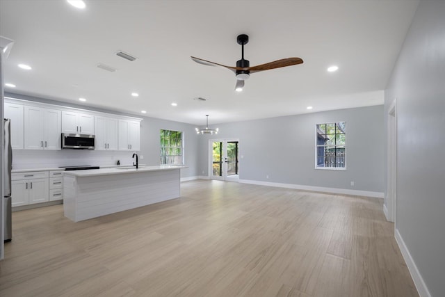 kitchen featuring sink, backsplash, a kitchen island with sink, white cabinets, and appliances with stainless steel finishes