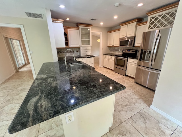 kitchen featuring kitchen peninsula, appliances with stainless steel finishes, dark stone counters, and sink