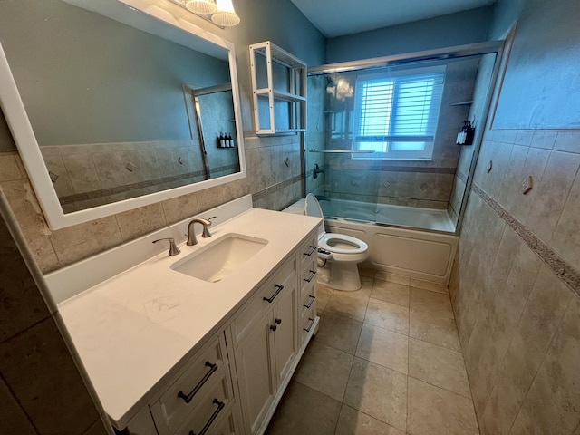 full bathroom featuring combined bath / shower with glass door, tile patterned floors, toilet, vanity, and tile walls