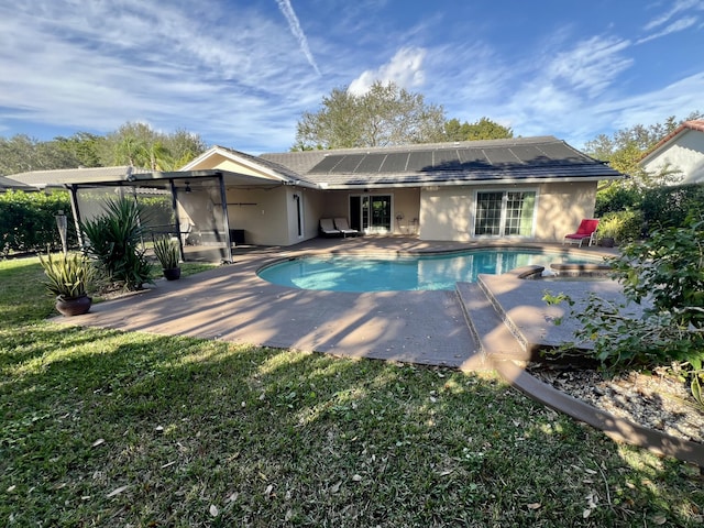 rear view of house with a yard, a patio, and solar panels