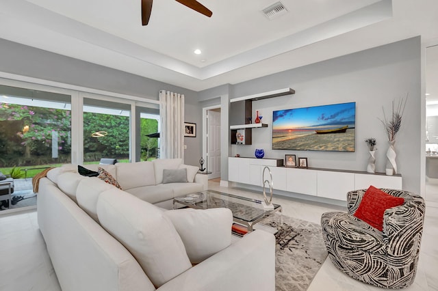 living room featuring a raised ceiling and ceiling fan